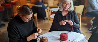 People knitting around a table from yarn shop, Knit With Me in Richmond UK.