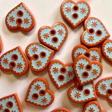 Heart-shaped ceramic tiles with decorative patterns on a light background