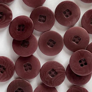 Close-up of multiple maroon buttons on a white background