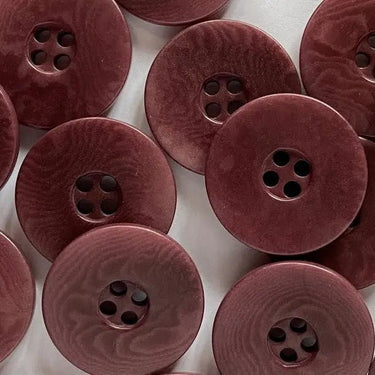 Close-up of maroon buttons with a textured surface on a white background