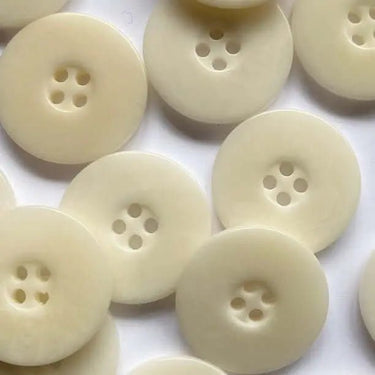 Close-up of multiple white buttons with four holes on a white background