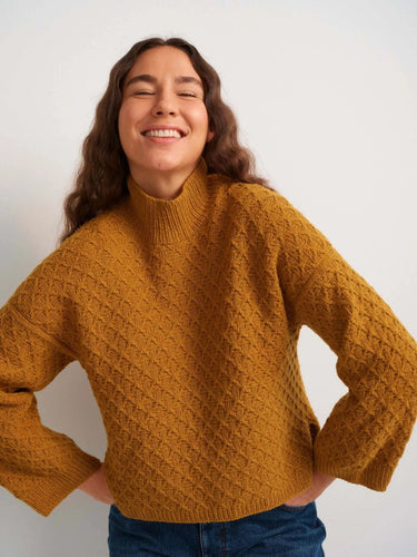 Smiling person wearing a knitted sweater, featured in 52 Weeks of Sweaters knitting book pre-order.