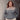 Person wearing a two-tone sweater standing against a concrete wall.