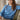 Woman wearing a blue sweater with floral patterns sitting on a couch.