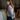 Woman in a gray cardigan standing in a room with wooden beams.
