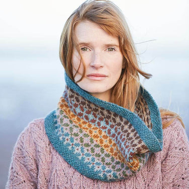 Woman wearing colorful knitted cowl, showcasing intricate patterns and textures.