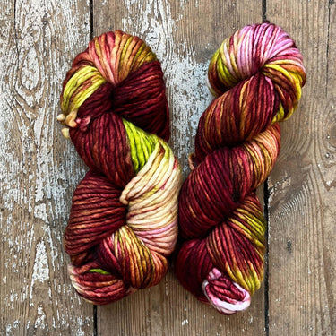 Two skeins of multicolored yarn on a wooden surface