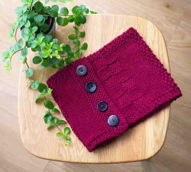 Knitted red scarf with buttons on a wooden table, perfect for Beginner Knitting Class.