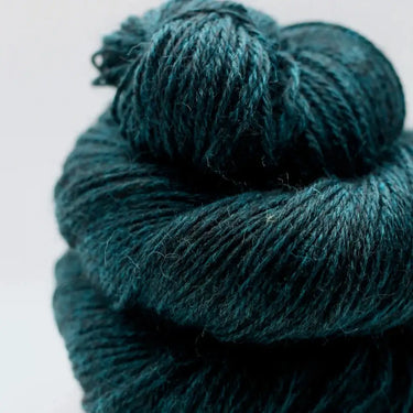Close-up of Yarnadelic Sport yarn in deep teal, spun from 100% Falklands Corriedale fiber, showcasing its soft texture and rich color.