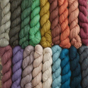 Colorful skeins of Yarnadelic Sport yarn in various shades, made from 100% Falklands Corriedale wool. Ideal for knitting and crafting.