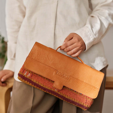 Person holding a stylish leather and woven handbag with a casual outfit