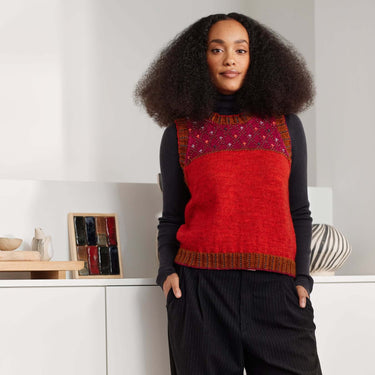 Model wearing a vibrant red beaded sweater vest, showcasing Beaded Colourwork knitting design by Jeanette Sloan.