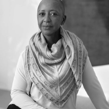 Author of Beaded Colourwork: A Modern Approach to Knitting, seated and wearing a knitted shawl.