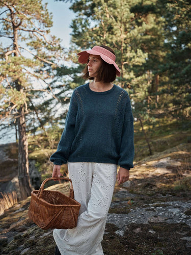 Woman in sweater and sun hat with basket in forest, featured in Laine Magazine's Spring Issue 28.