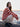 Woman wearing striped knit sweater from Art of the Sea - 23 Knitwear Designs Inspired by the Moonins by Laine, sitting by the sea.