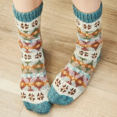 Colorful knit socks with intricate patterns on a wooden floor.