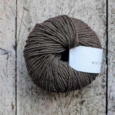 Knitting for Olive Heavy Merino yarn ball in natural brown on rustic wood surface.