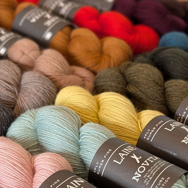 Assorted skeins of yarn with 'Laine Novia' labels in a close-up shot.