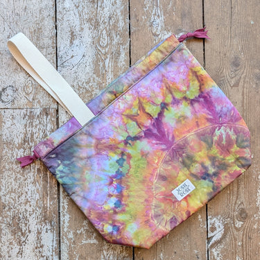 Ice Dyed Project Bags - XLarge shown on wooden floor, multicolored tie-dye effect, Jose Rose brand, with strap and zipper closure.
