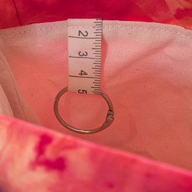 Interior of Ice Dyed Project Bags - XLarge showing lining and pocket with ring tab detail in a pink and red color pattern.