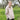 Woman wearing a beige knitted sweater in a grassy outdoor setting. Tukubook knitting book
