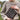 Person wearing a patterned sweater holding a knitted square outdoors. Tukubook knitting book