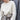 Person wearing a white knitted sweater from the Tukubook collection, showcasing Finnish knitting design with subtle textures. Tukubook knitting book