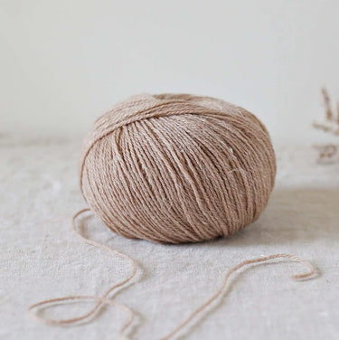 Alice | De Rerum Natura yarn ball, blend of organic Mérinos d'Arles and linen, showcasing softness, elasticity, and luminous appearance. Button
