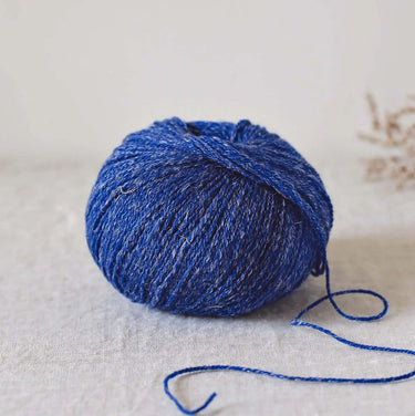 Alice | De Rerum Natura yarn ball in blue with elastic, luminous texture, featuring organic Mérinos d'Arles wool and linen blend.