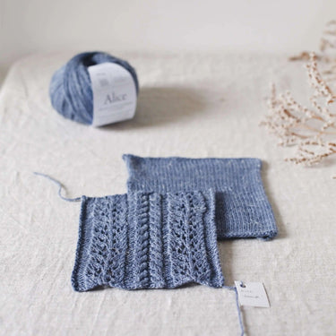 Close-up of Alice | De Rerum Natura yarn swatches and ball showcasing merino and linen blend with button detail