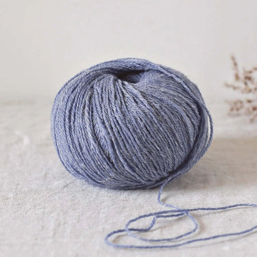 Alice | De Rerum Natura yarn in blue, made from organic Mérinos d'Arles and linen, providing elasticity and softness. Focus on unique button.