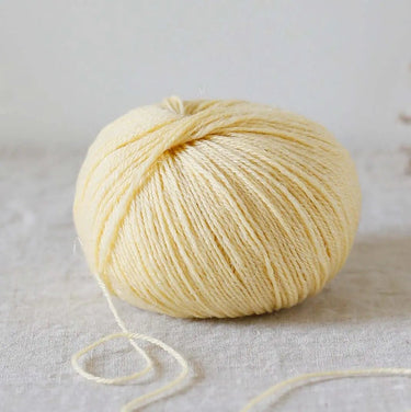 Ball of Alice | De Rerum Natura yarn, 75% organic merino, 25% linen, elastic and soft with a luminous finish, resting on fabric surface.