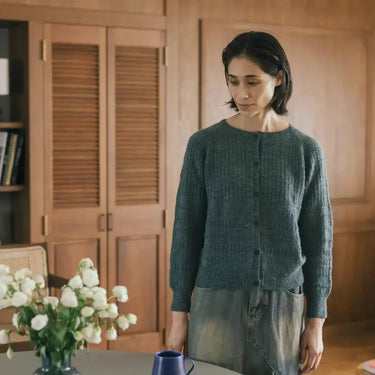 Woman wearing Amirisu sweater from Assemblage Vol. 2 in a cozy room.