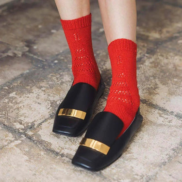 Vibrant red socks featured in Amirisu Sock Knitting Club pattern book, showcased with stylish black loafers.