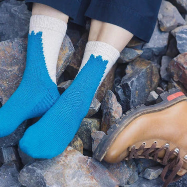 Blue and cream socks on rocks, featured in the Amirisu Sock Knitting Club.