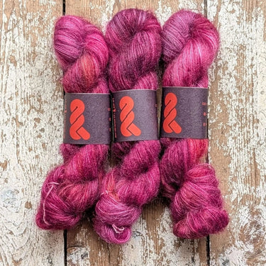 Three skeins of A&P Lace Silk Mohair yarn in vibrant pink hues, showcasing its luxurious fluffiness and hand-dyed unique colors.
