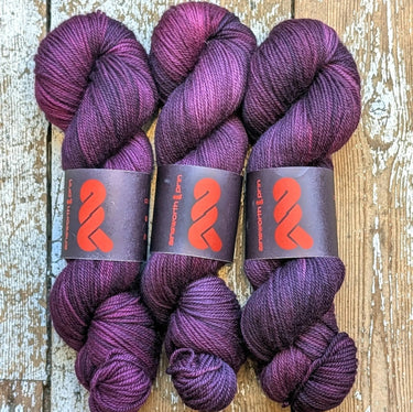 Hand-dyed A&P Plump Sock DK yarn in rich purple tones, perfect for soft, durable accessories like socks and hats.