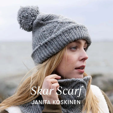 Woman wearing Skar Scarf and chunky knit beanie by Janita Koskinen at the beach.