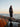 Woman wearing Art of the Sea knitwear standing on rocks by the sea during sunset.