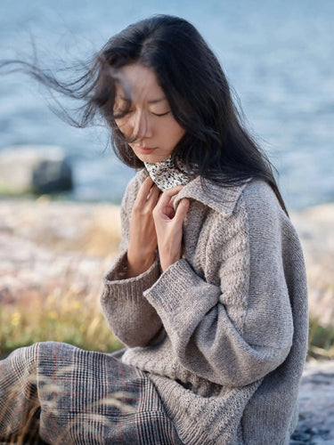 Woman wearing knitwear inspired by The Art of the Sea, sitting by the ocean.