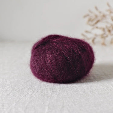 Bérénice lace weight yarn in rich burgundy, featuring extra-fine Angora goat fibres and organic Merinos d'Arles, with a shiny silk yarn.