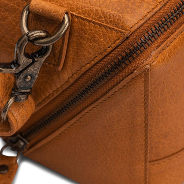 Close-up of a brown leather bag with a zipper and handle on a white background