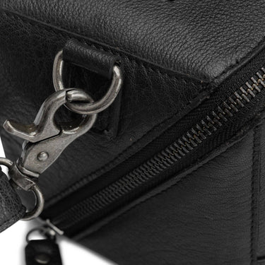 Close-up of a black leather bag with a zipper and clasp on a white background