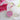Pink polka-dot Row Counter with push button by KnitPro, resting on a floral background.