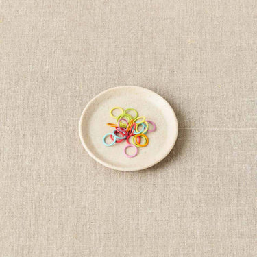 Cocoknits Magnetic Notions Dish holding colorful stitch markers, ideal for organizing small metal notions for knitters and crafters.