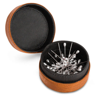 Wooden pin cushion with black interior and pins on a white background