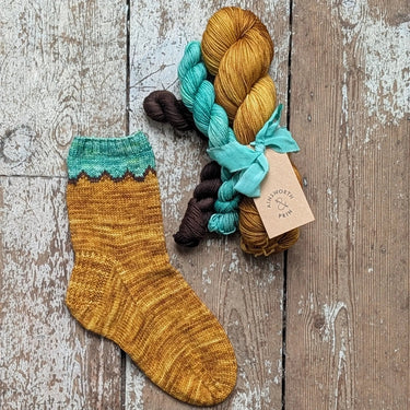 Ainsworth & Prin classic sock Flower Yarn Knitting kits with colorful skeins and silk ribbon, displayed on a wooden surface.