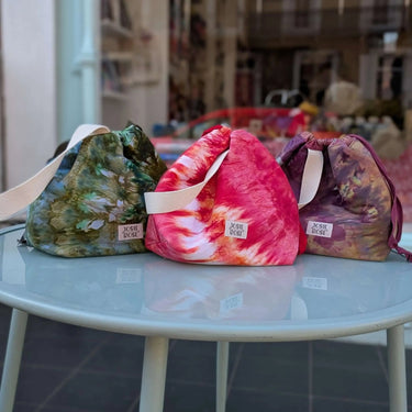 Colorful ice dyed Craft Project Bag collection on display table with unique designs and lined interiors for organization.
