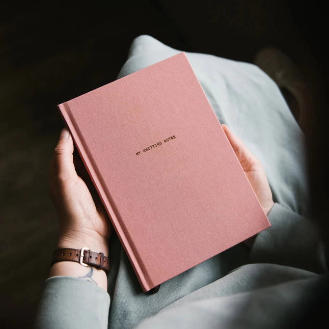 Knitting Book in a persons lap with pink cover