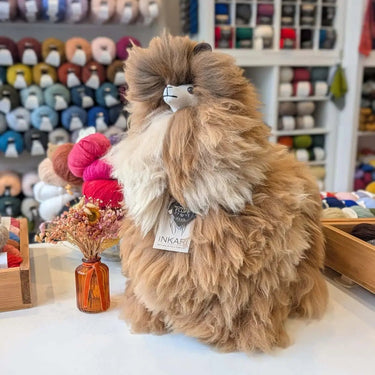 Fluffy Inkari Stuffed Alpaca Animal in a yarn store setting